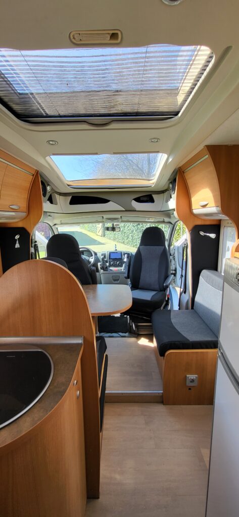 Gerenoveerd camper interieur met op maat gemaakte kussens en hoogwaardige stoffering in moderne stijl.