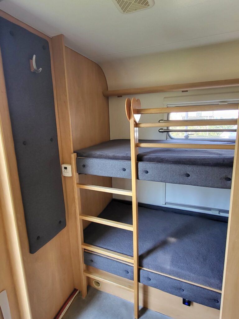 Gerenoveerd camper interieur met op maat gemaakte kussens en hoogwaardige stoffering in moderne stijl.