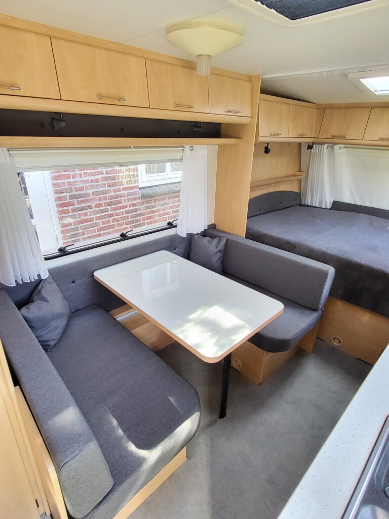 Gerenoveerd camper interieur met op maat gemaakte kussens en hoogwaardige stoffering in moderne stijl.
