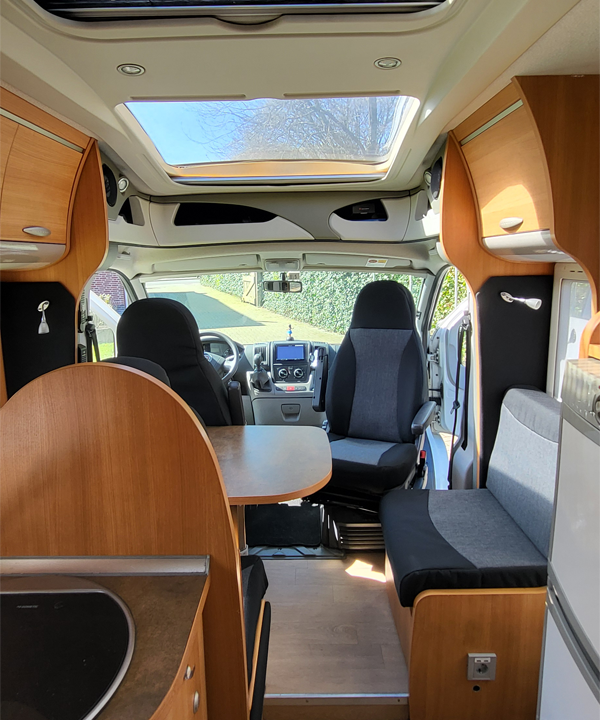 Gerenoveerd camper interieur met op maat gemaakte kussens en hoogwaardige stoffering in moderne stijl.